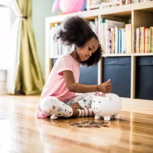 young girl putting change into a piggybank
